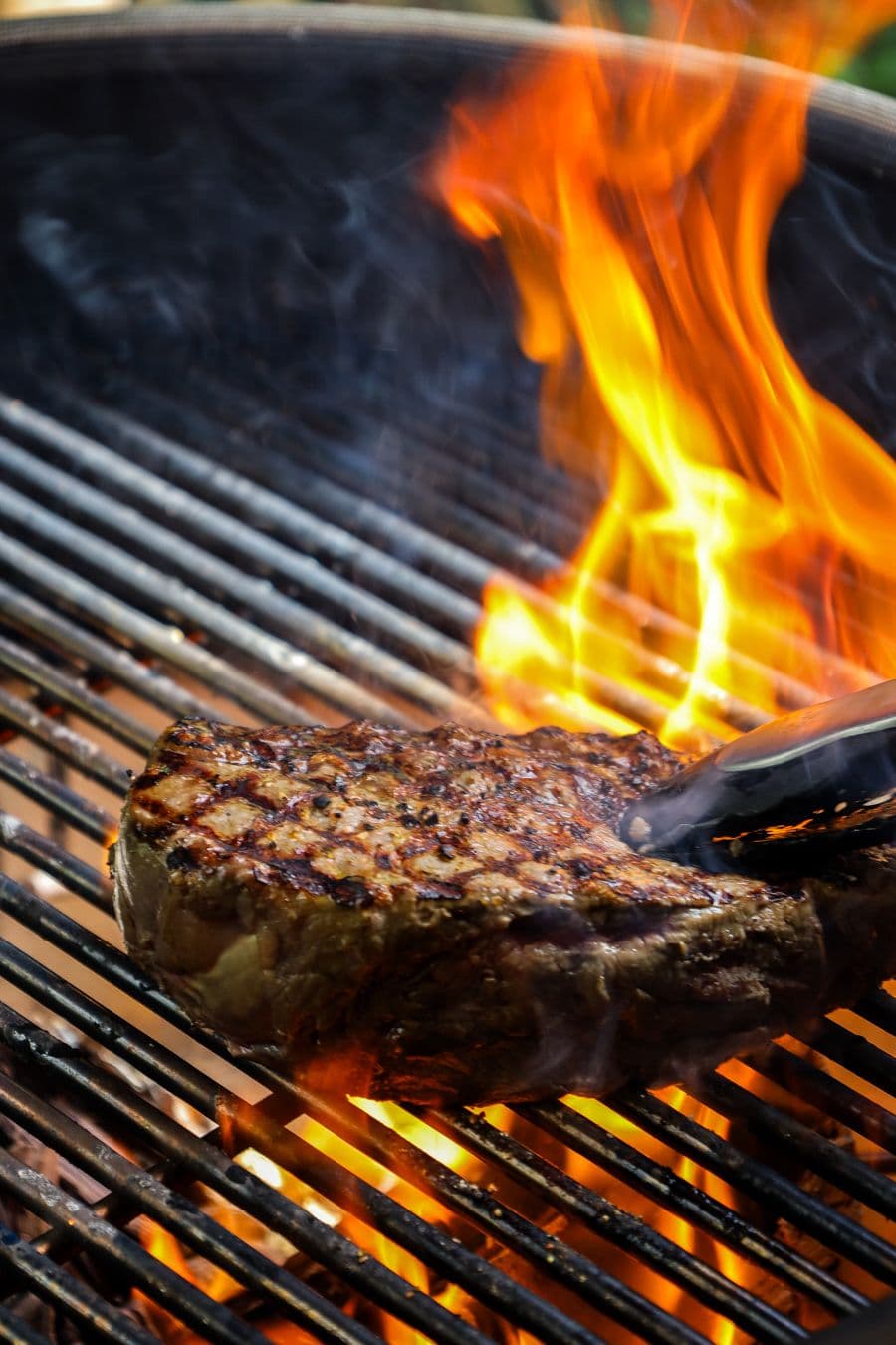 Steak die boven open vuur op de barbecue wordt gegrild